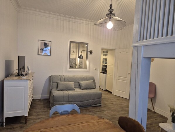 A cozy room with a sofa, a small table, a cabinet, and a ceiling light fixture.