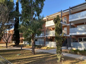 Stunning multi-story building with balconies and terraces, set amidst lush greenery.