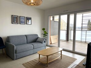 Relax in this stylish living room with a sofa, framed artwork, and sliding glass door leading to a balcony.