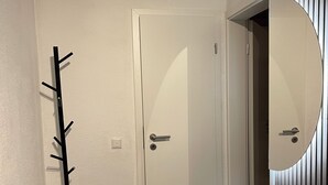 A hallway with a coat rack, a door, and a mirror.