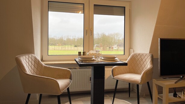 A dining area with two chairs, a table, and a TV.