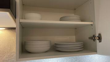 Ein Küchenschrank mit Regalen voller Teller und Schüsseln.