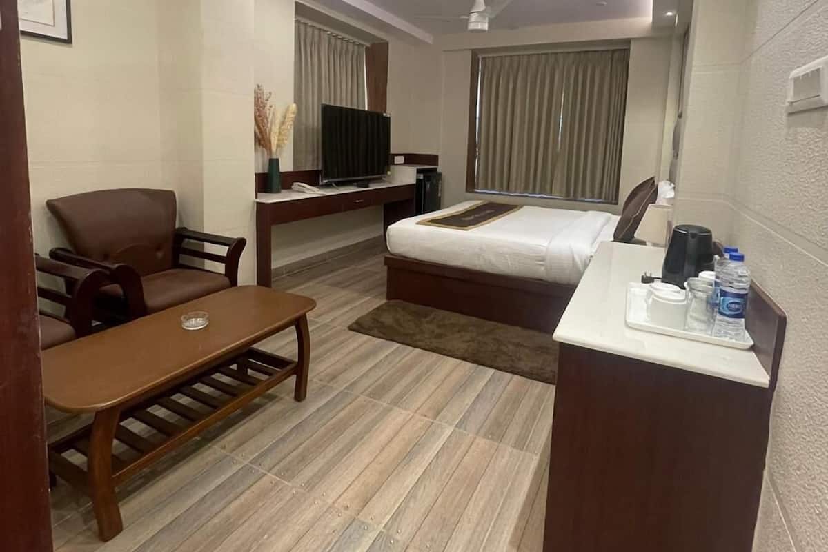 A hotel room with a bed, a desk, a chair, a TV, and a ceiling fan.