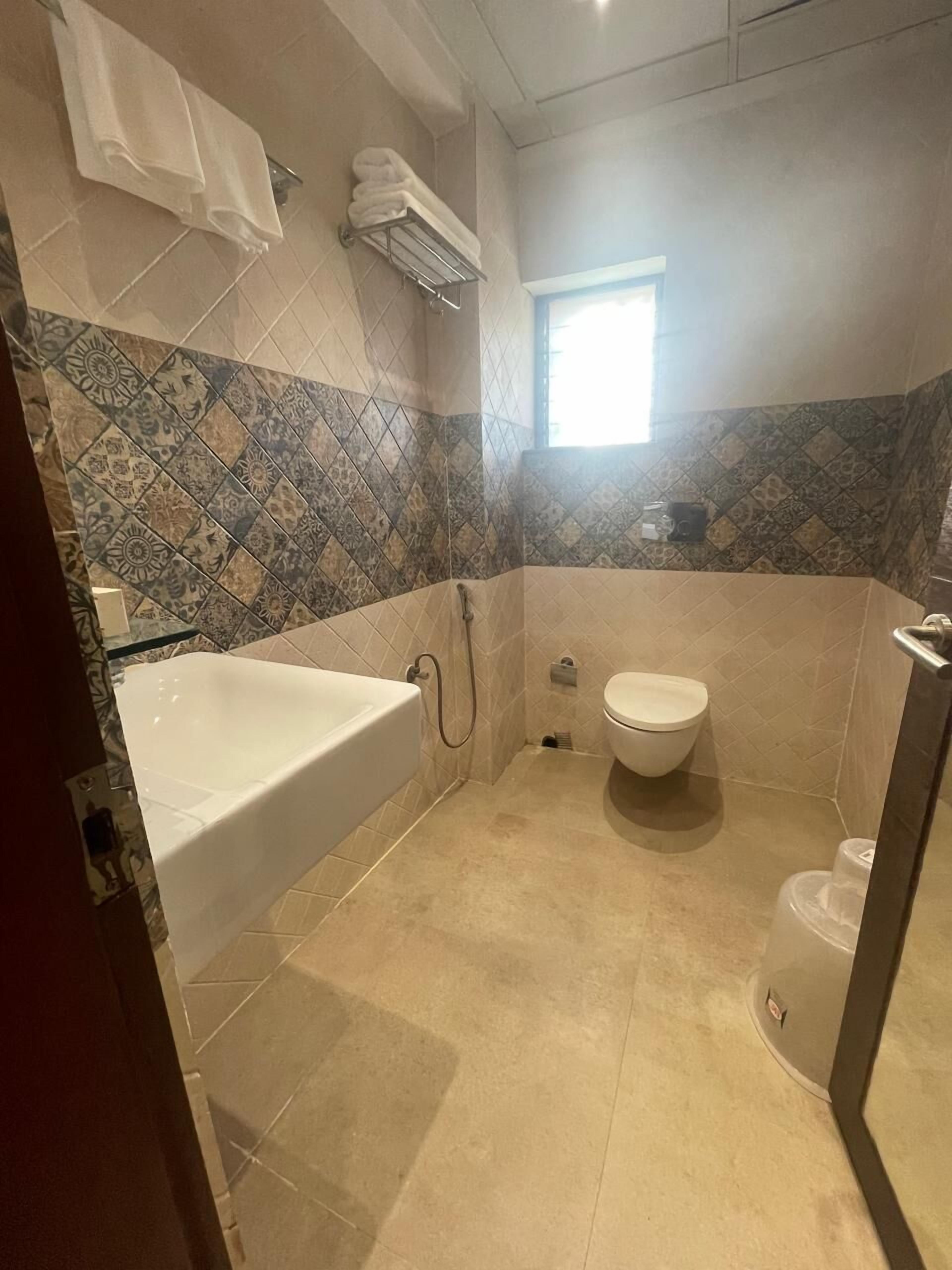 A bathroom with a bathtub, toilet, and a window.