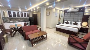 A modern hotel room with a bed, a sofa, a dining table, and a kitchen area. - The Crystal Newtown Kolkata (Barasat)