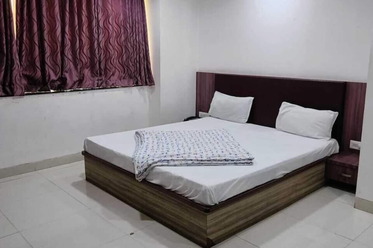 Un dormitorio con cama, mesita de noche, ventilador de techo y ventana con cortinas.