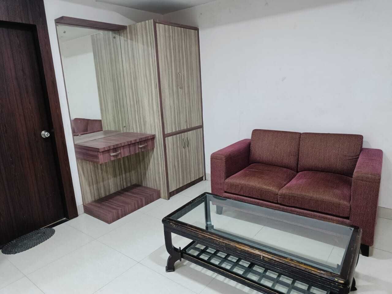 A living room with a red sofa, a glass coffee table, and a wardrobe with a mirror.