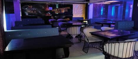 A restaurant with booths and tables, a stage with a banner, and a modern interior design.