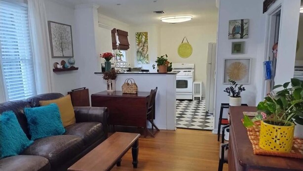 Una sala de estar con un sofá de cuero marrón, una mesa de centro de madera y una zona de comedor con una mesa y sillas de madera.