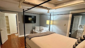 Ein Schlafzimmer mit einem Himmelbett, einem flachbildfernseher an der Wand und einem begehbaren Kleiderschrank.