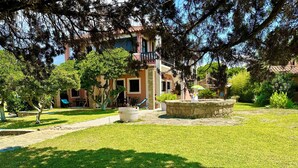 A courtyard with a fountain, a stone bench, and a building with a balcony. - Genari Beach Apartments Sea View Apartment for Couples or Small Families (Pyrgos)
