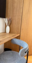 Una silla con respaldo de tela gris y un estante de madera al fondo.