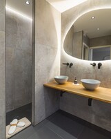 Un baño moderno con un espejo grande, dos lavamanos y un perchero para toallas.