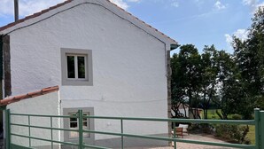 Un bâtiment blanc avec une petite fenêtre et un portail vert à l’avant.