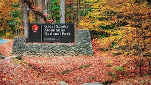 A sign for Great Smoky Mountains National Park with a stone base and a logo. - 3BR Gatlinburg*Firepit*Hot Tub*Privacy + Quiet! (Gatlinburg)