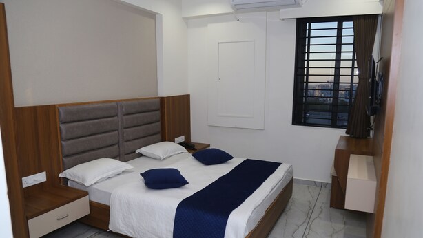 Un dormitorio ordenado con cama, mesitas de noche, armario y ventana con vistas.