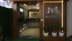 Entrada de un hotel con un letrero de 'Welcome', un letrero de 'Hotel Top 4' y plantas en macetas.