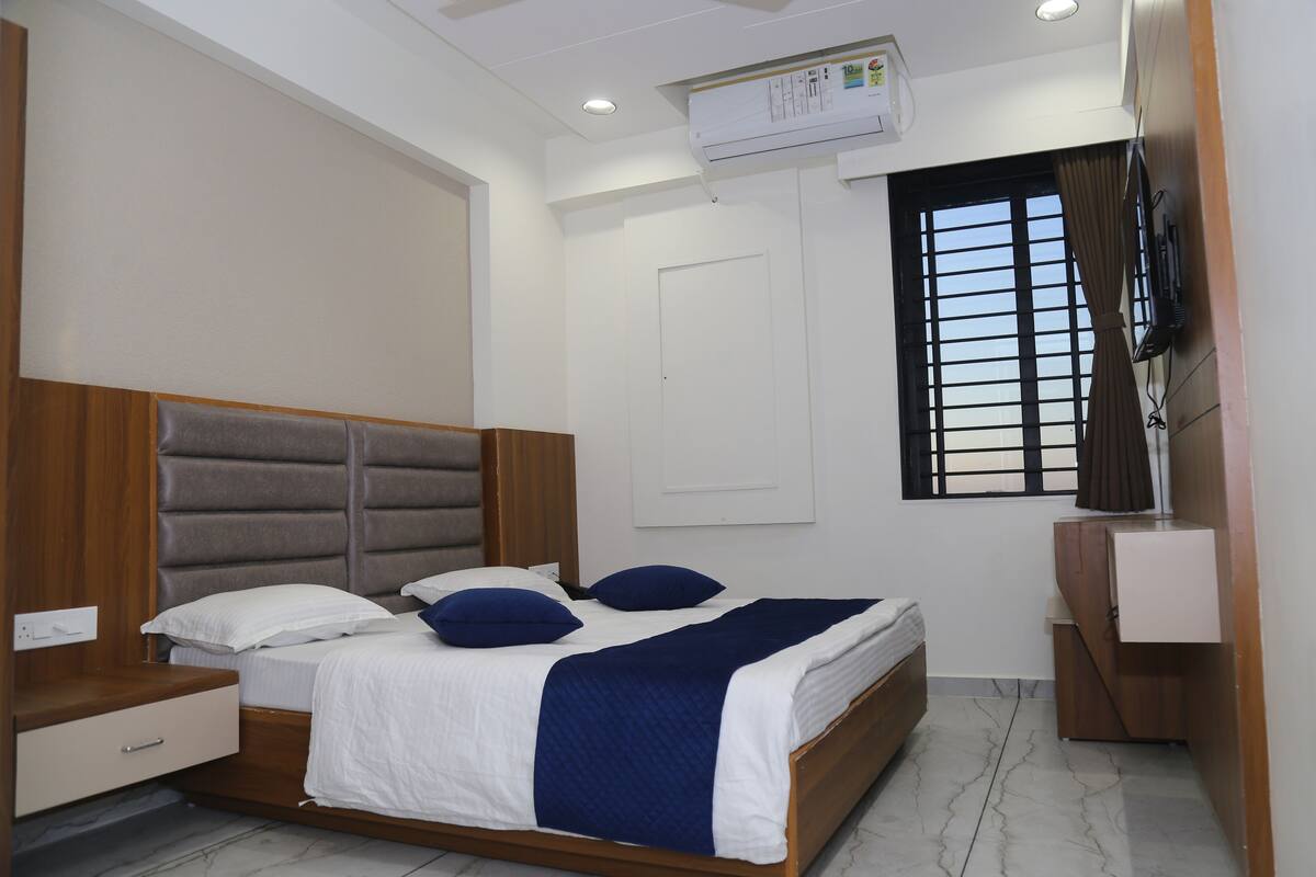 Quarto com cama, mesa de cabeceira, cômoda e janela com persianas.