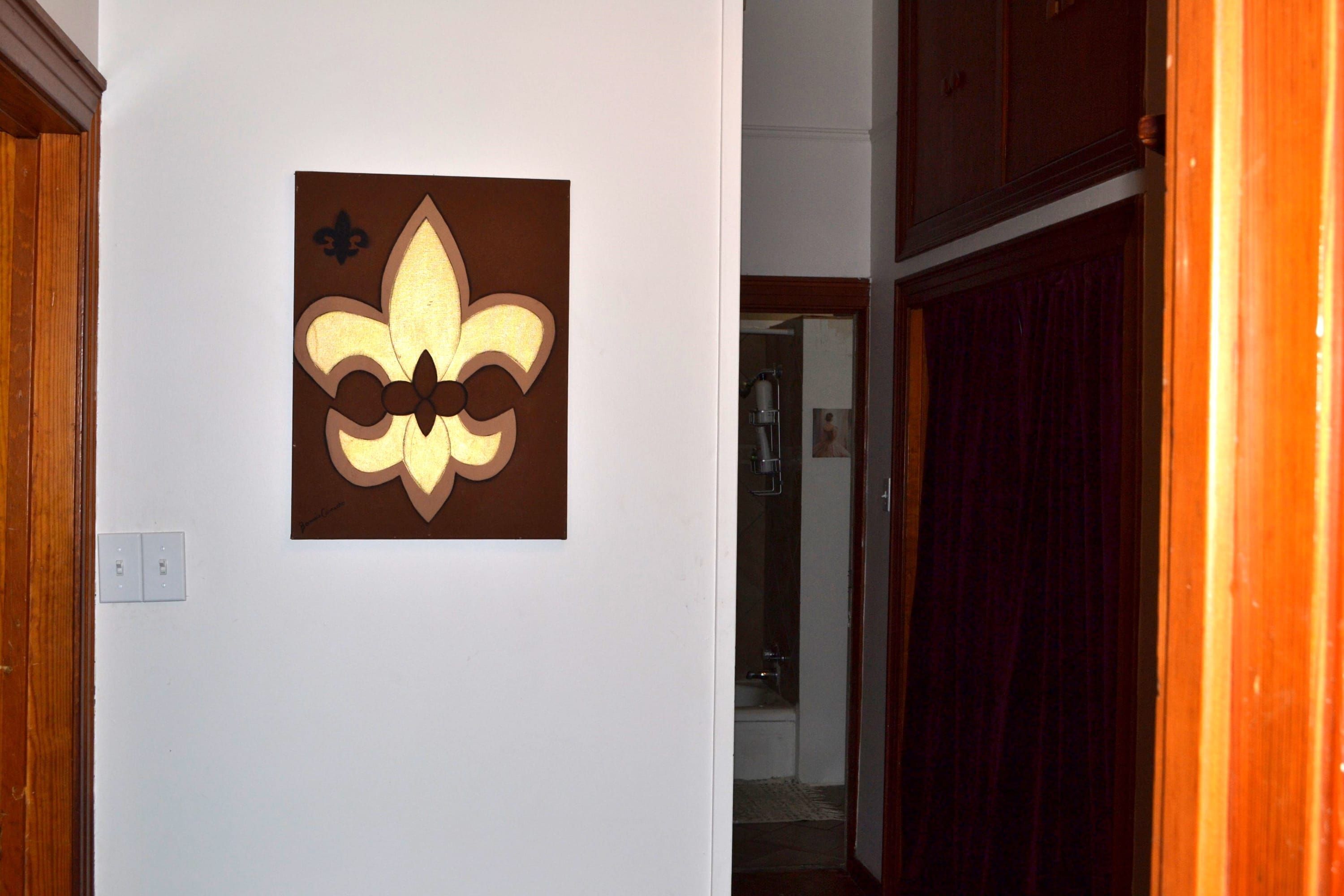 A wall-mounted fleur-de-lis symbol on a white wall.