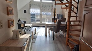 Un apartamento moderno con comedor, cocina y escalera.