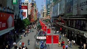 A busy urban street with various shops and advertisements.
