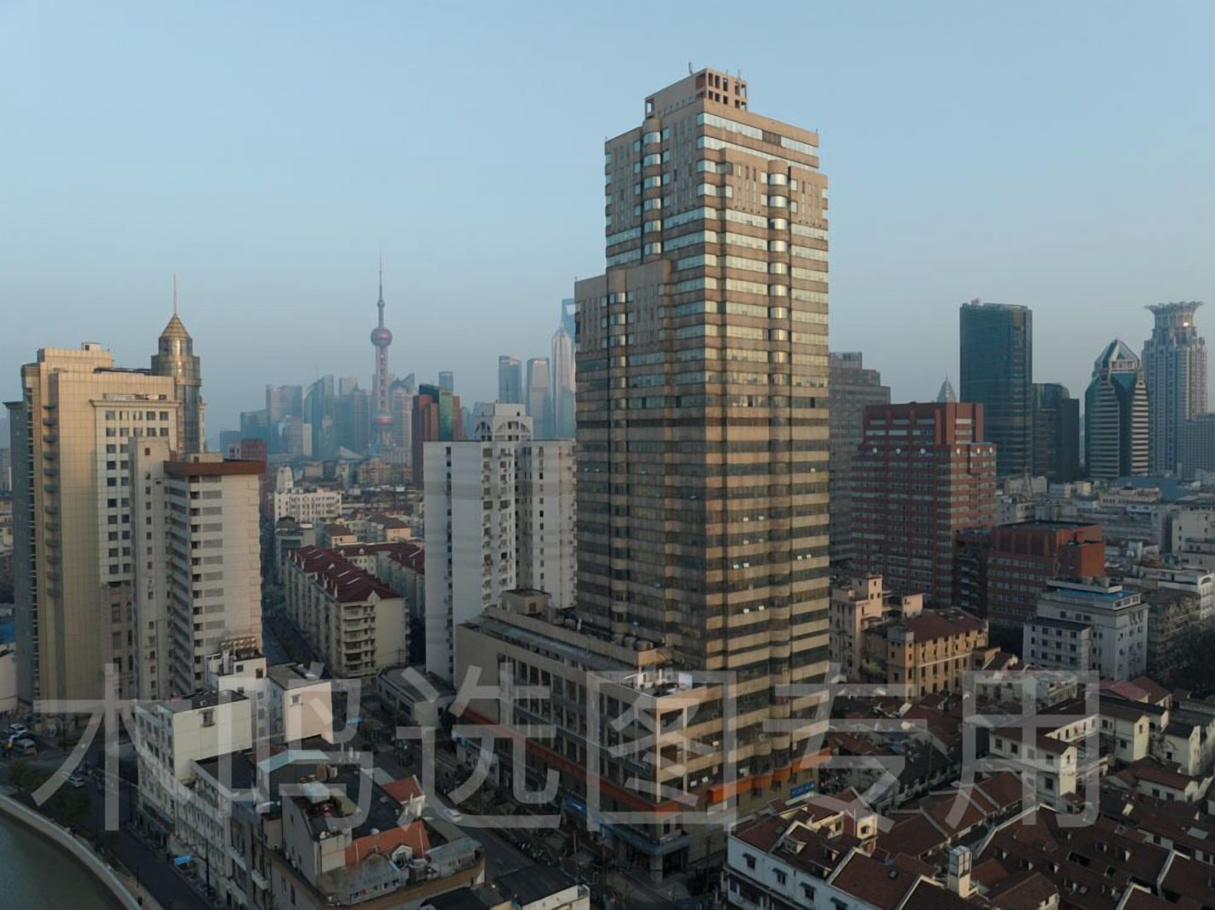 A high-rise building with a modern architectural design, surrounded by other buildings and a clear sky.