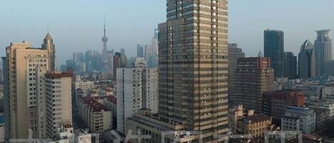 A high-rise building with a modern architectural design, surrounded by other buildings and a clear sky.