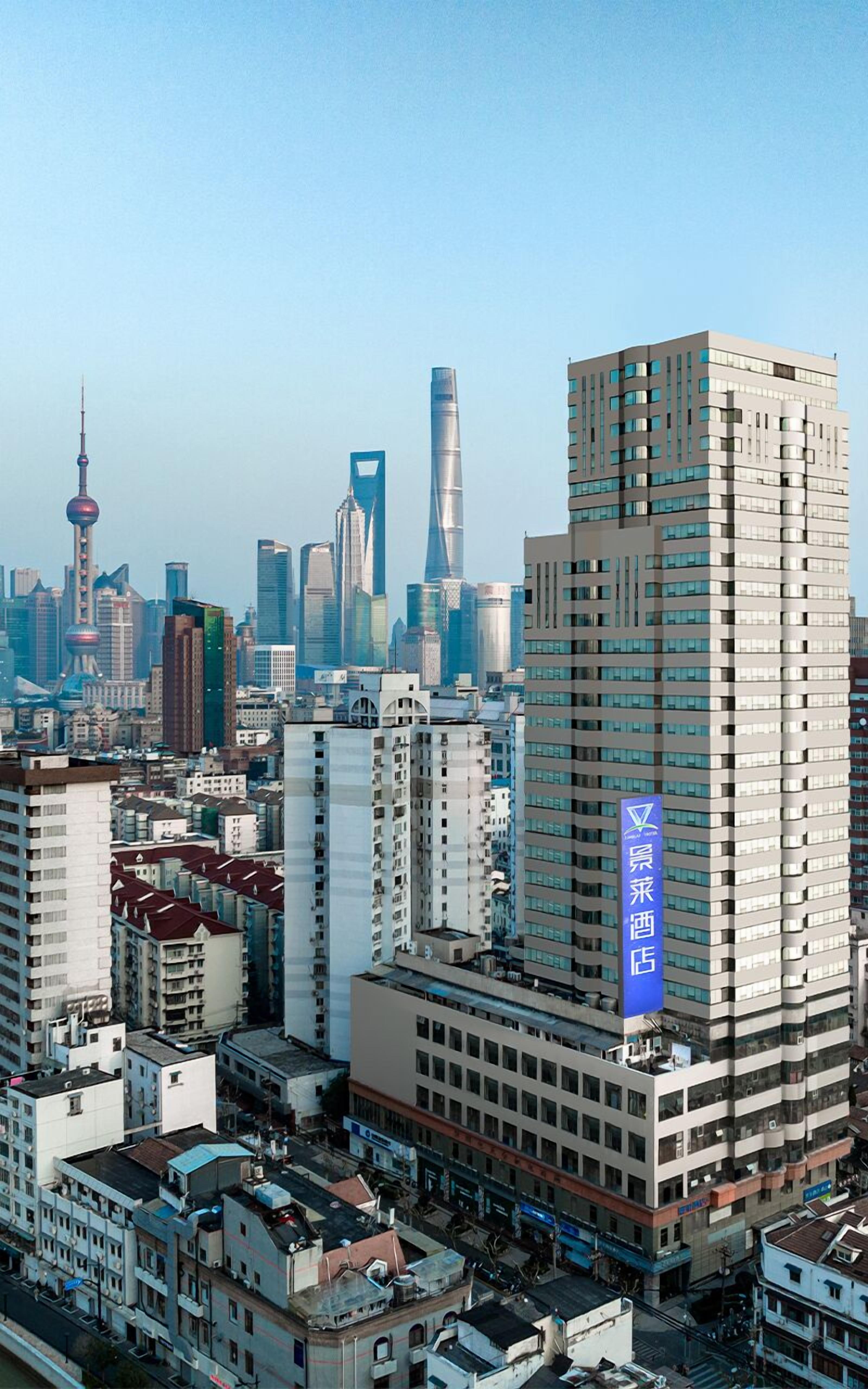 A high-rise hotel with a prominent blue sign, surrounded by other buildings and skyscrapers in a cityscape.