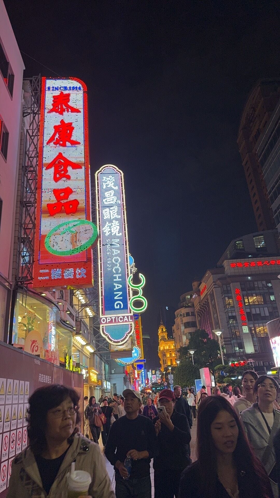 Een levendige stadstraat 's nachts, met verlichte reclameborden en gebouwen.