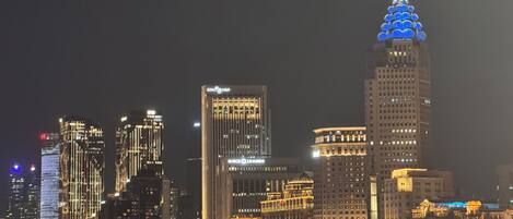 A nighttime cityscape with illuminated skyscrapers and a river reflecting the lights.