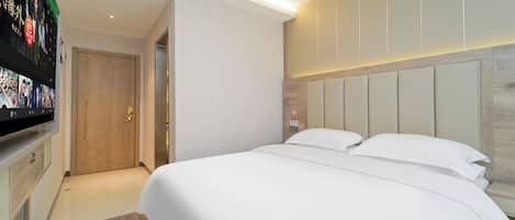 Una habitación de hotel con una cama grande, un televisor montado en la pared y una puerta de madera.