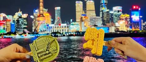 A night view of a city skyline with illuminated buildings and a river in the foreground.