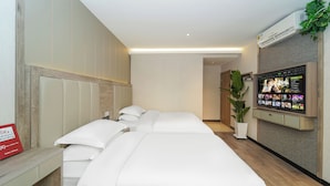 Une chambre d’hôtel avec un grand lit, un téléviseur fixé au mur et une plante en pot.