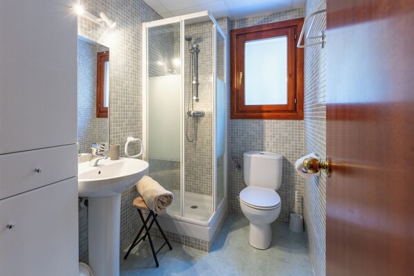 A bathroom with a shower, toilet, sink, and a wooden-framed window. - Andorra Stunning Views Apartment (El Tarter)