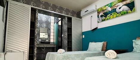 A hotel room with two beds, a tiled floor, a painting on the wall, and an air conditioning unit.