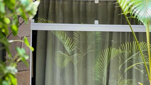 A room with a large window, a stone wall, and a view of palm trees outside. -  Pousada Ventos do Norte - Morro de São Paulo (Morro de São Paulo)