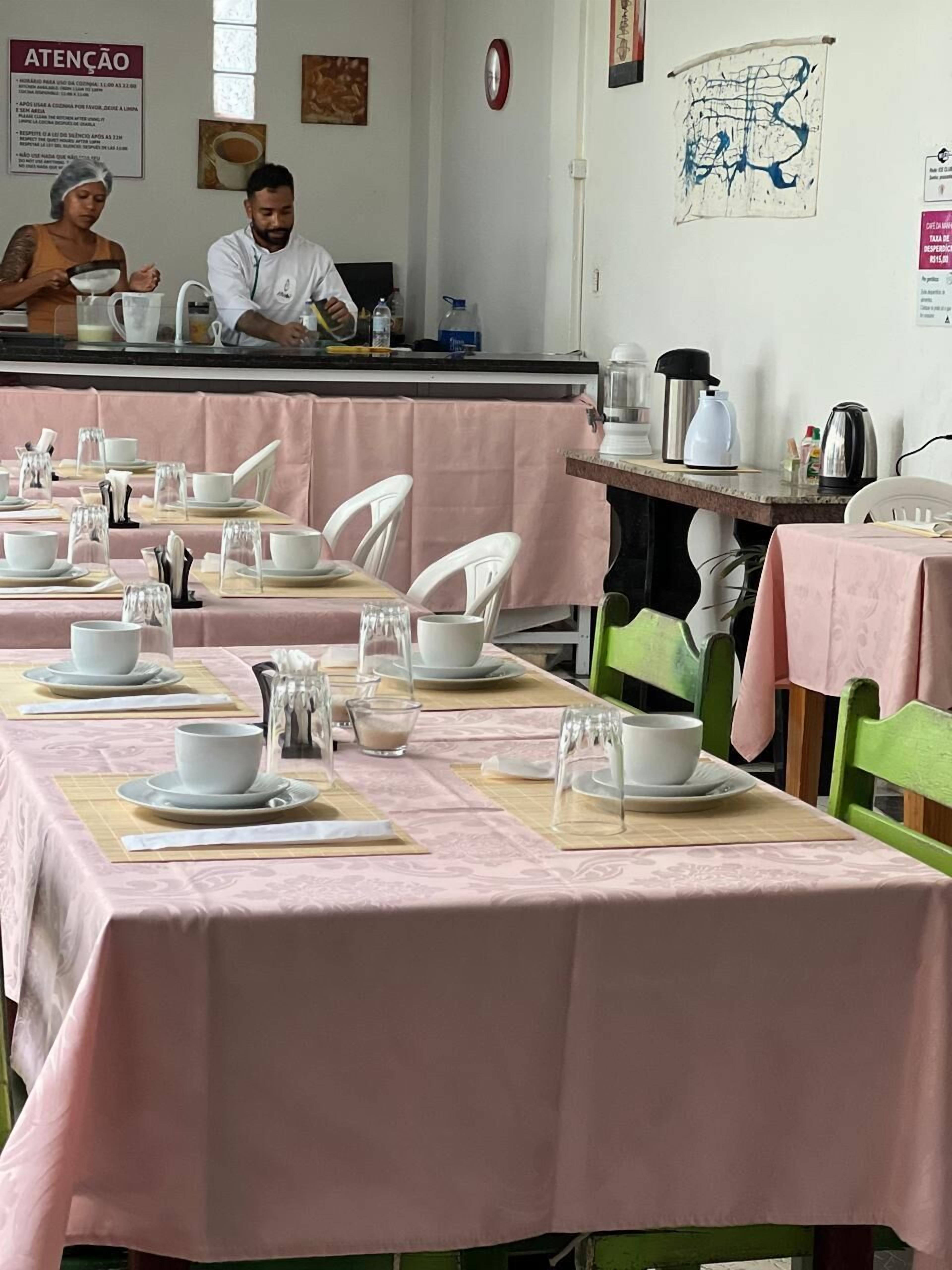 A restaurant with tables set for dining, a kitchen area, and a wall with a map and a clock.