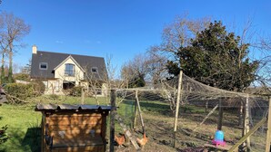 A wooden chicken coop with a blue feeder and a wire mesh enclosure in a backyard. - Spacious and bright house on large plot 10 min walk from Pont L' Abbé (Pont-l'Abbé)