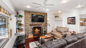 A modern living room with a fireplace, a large flat-screen TV, a ceiling fan, and a comfortable seating area. - Fasching Haus 190 (Aspen)