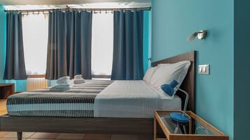 Un hotel moderno con una cama grande, una mesita de noche, una lámpara y vistas de la ciudad a través de amplios ventanales.