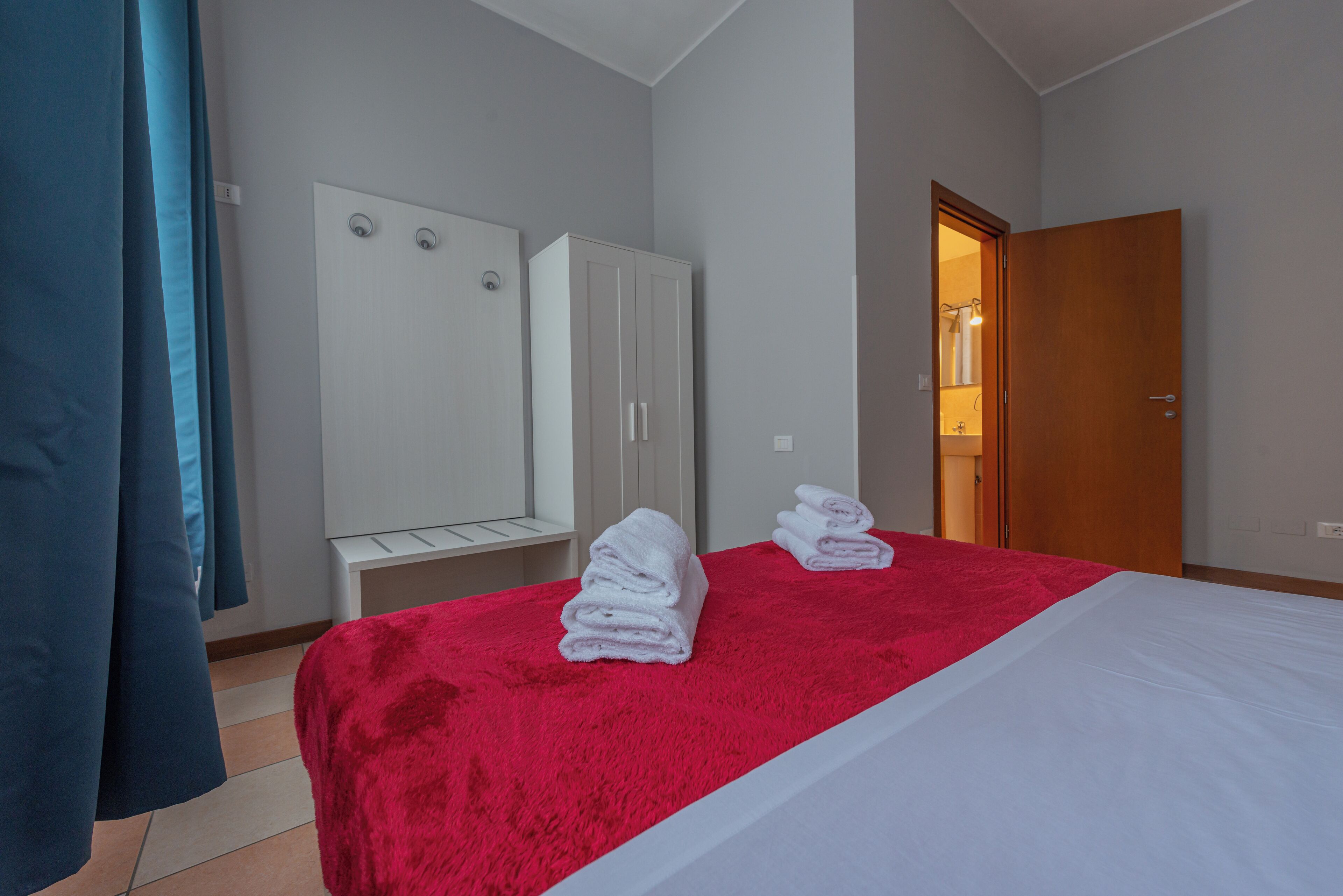 Een hotelkamer met een bed, een kledingkast en een badkamer, zichtbaar door een open deur.