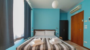Een hotelkamer met een groot bed, een houten kast, een nachtkastje en een wandairconditioner.