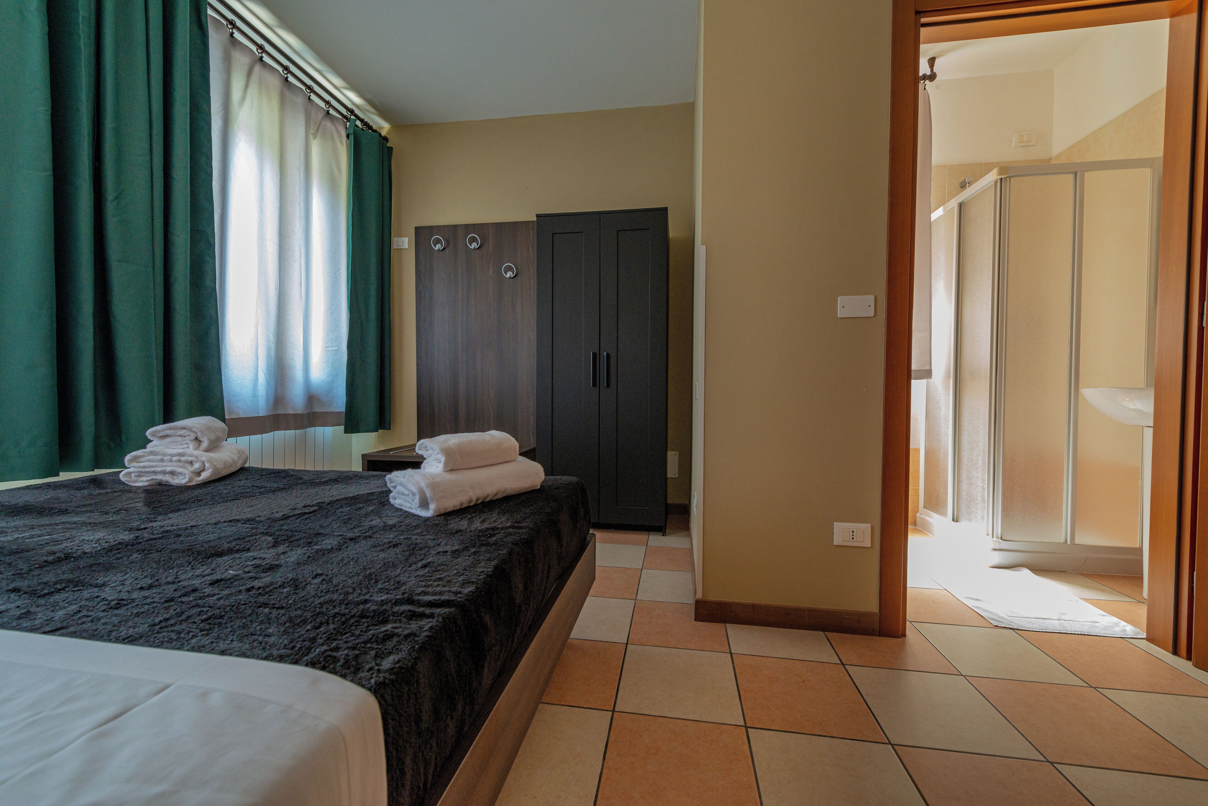 Ein Hotelzimmer mit Bett, Kleiderschrank und Duschbereich.