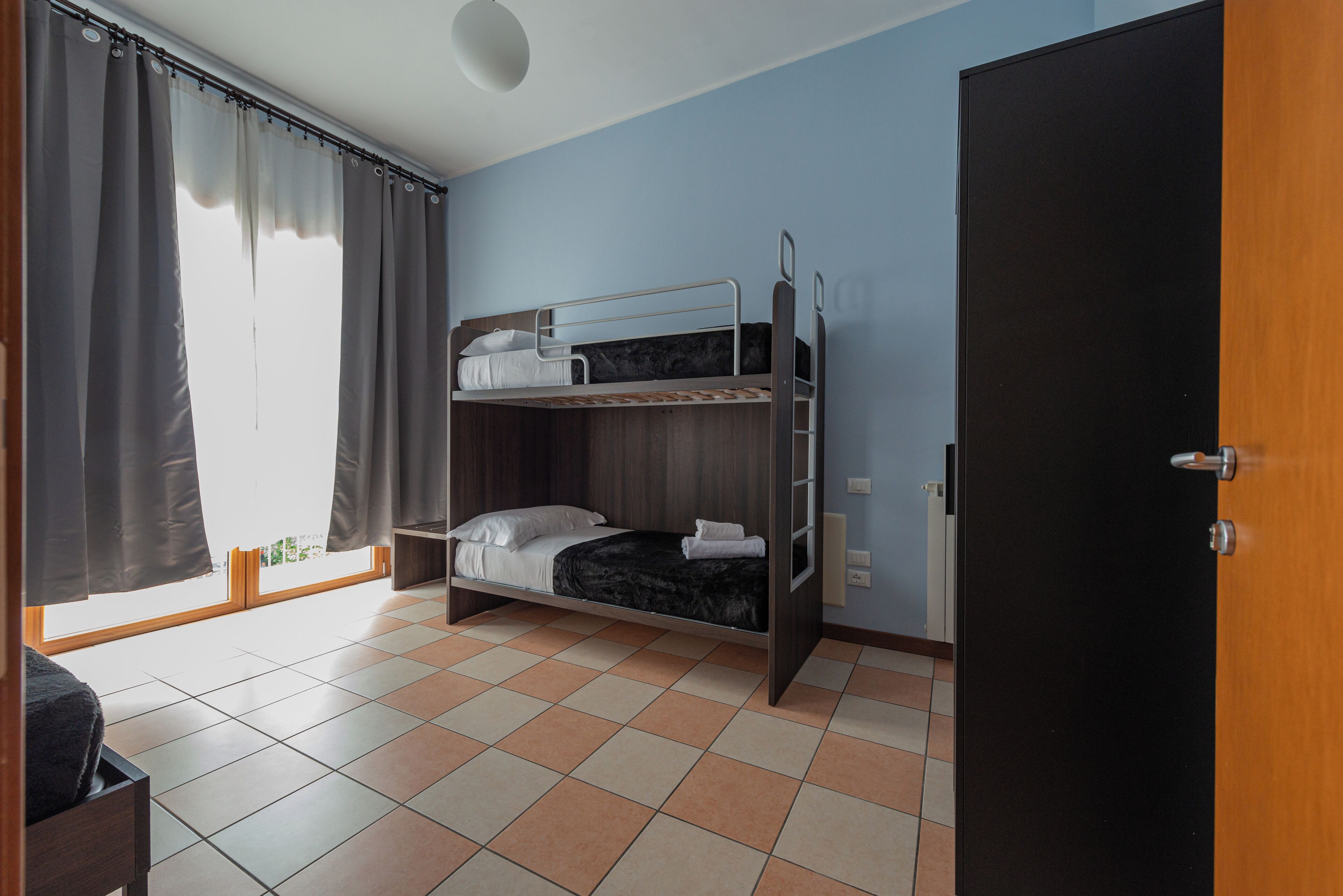 Una habitación con literas, una puerta de madera y piso de baldosas.