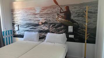 A bedroom with a large mural of a kayaker on water, a bed with white linens, and a wooden coat rack.