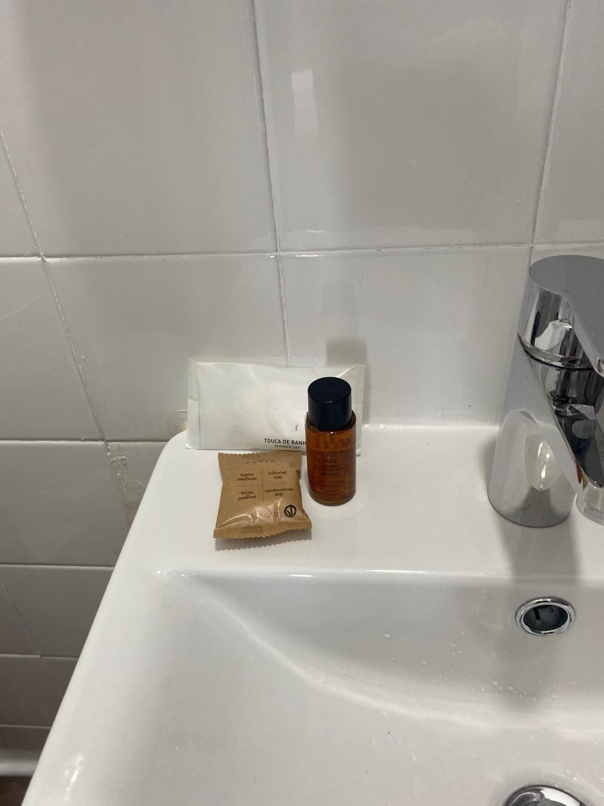 Un lavamanos con una botella de jabón líquido, una pastilla de jabón y una caja de pañuelos.