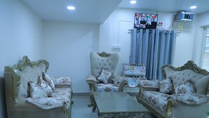 A living room with two ornate sofas, a coffee table, and a television mounted on the wall. - samudra inn (Nalgonda)