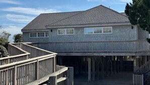 Een tweelaags huis met een overdekte garage en een houten terras.