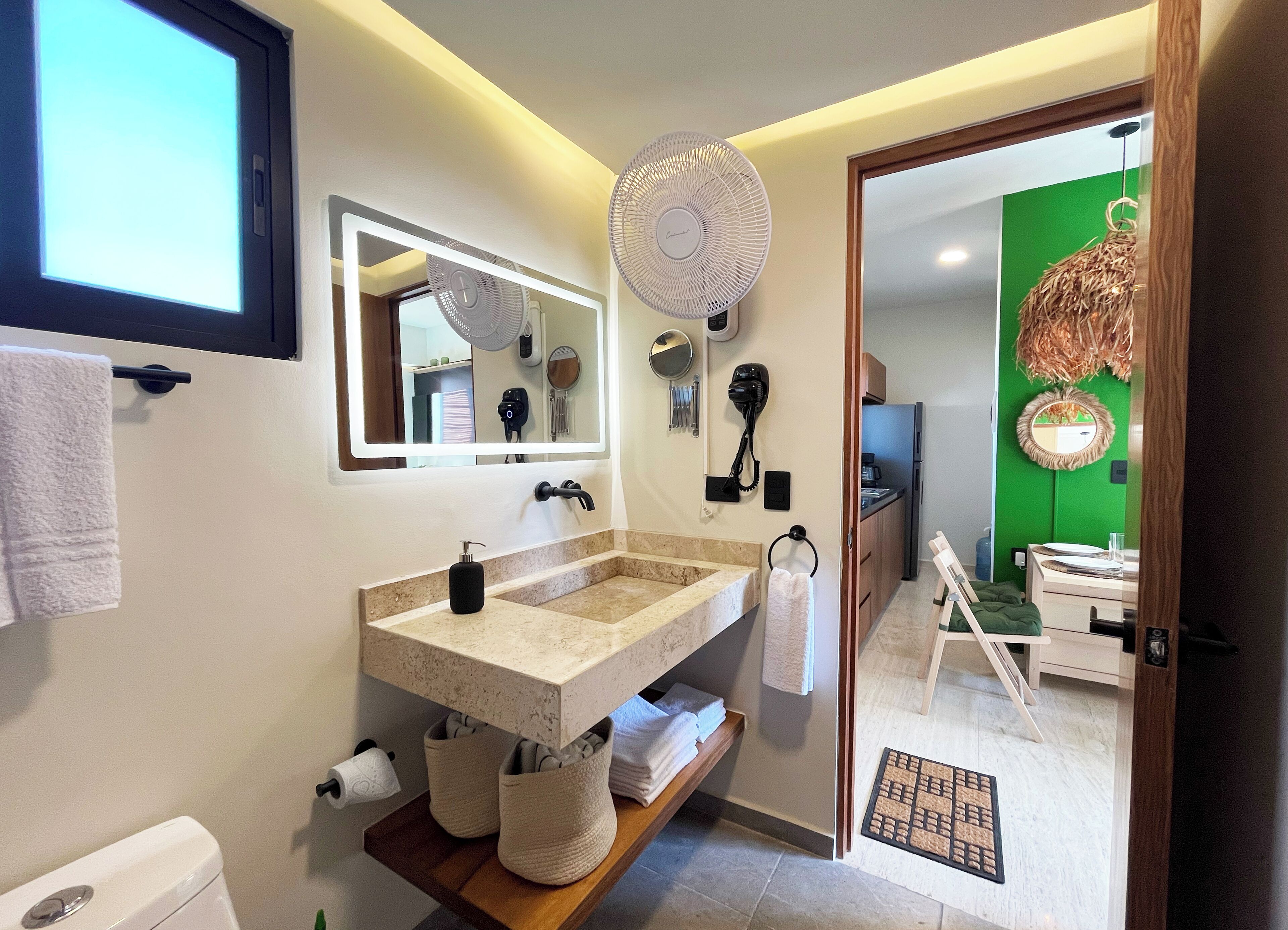 Un bagno moderno con un lavandino ampio, uno specchio, un asciugacapelli e una ventola.