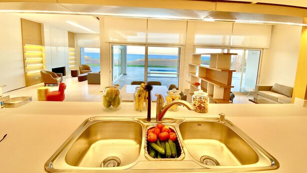 Een moderne keuken met een grote spoelbak, een eetgedeelte met uitzicht en een woonkamer met open haard.